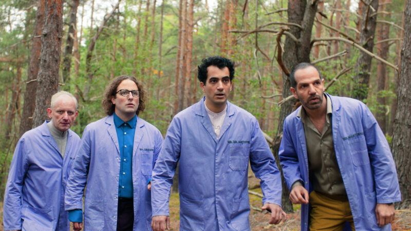 Four men in blue overalls, in the forrest, looking surprised and scared